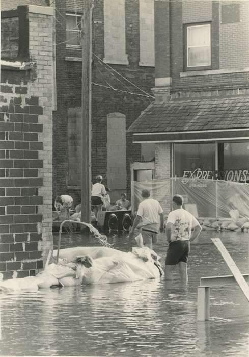 brick building, Floods, Cities and Towns, Waverly Public Library, Iowa History, power lines, Civic Engagement, Portraits - Group, Waverly, IA, sandbag, Iowa, tarp, store, history of Iowa, Motorized Vehicles, Businesses and Factories