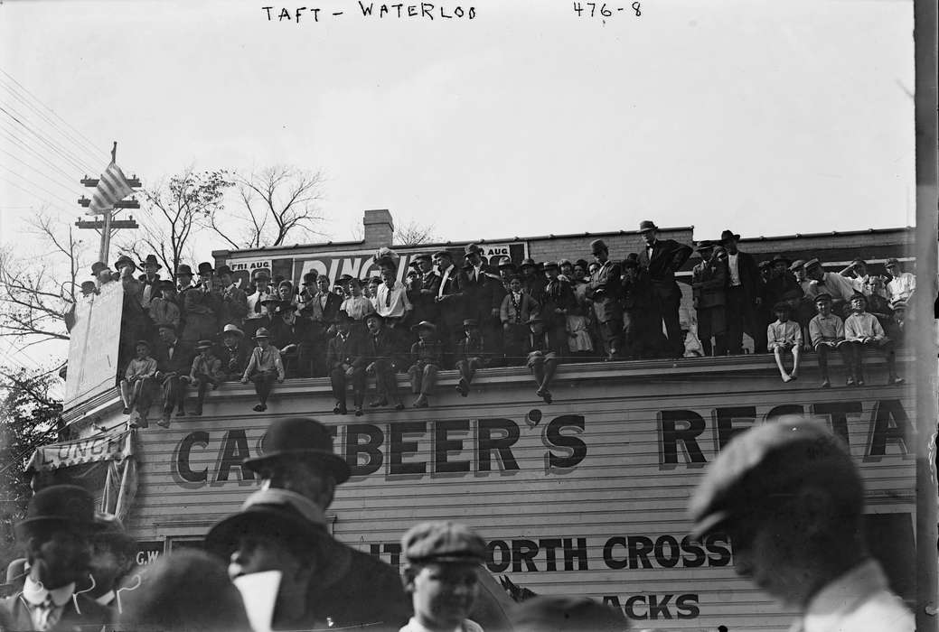 Entertainment, sign painting, roof, Businesses and Factories, Portraits - Group, Children, Iowa, Civic Engagement, Main Streets & Town Squares, Iowa History, overlook, crowds, Cities and Towns, Library of Congress, Families, hats, history of Iowa, store front, Leisure, restaurant