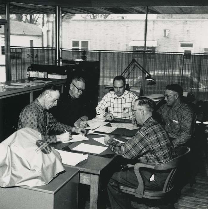 building interior, table, Labor and Occupations, Iowa, Iowa History, window, lamp, Waverly, IA, history of Iowa, Waverly Public Library, laundromat, man, glasses, plaid shirt, office chair, Portraits - Group, Businesses and Factories, brick building, curtain