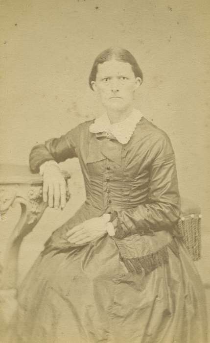 table, lace collar, woman, frown, Olsson, Ann and Jons, carte de visite, collared dresses, Iowa History, Mount Pleasant, IA, hoop skirt, dropped shoulder seams, Portraits - Individual, Iowa, bow tie, history of Iowa