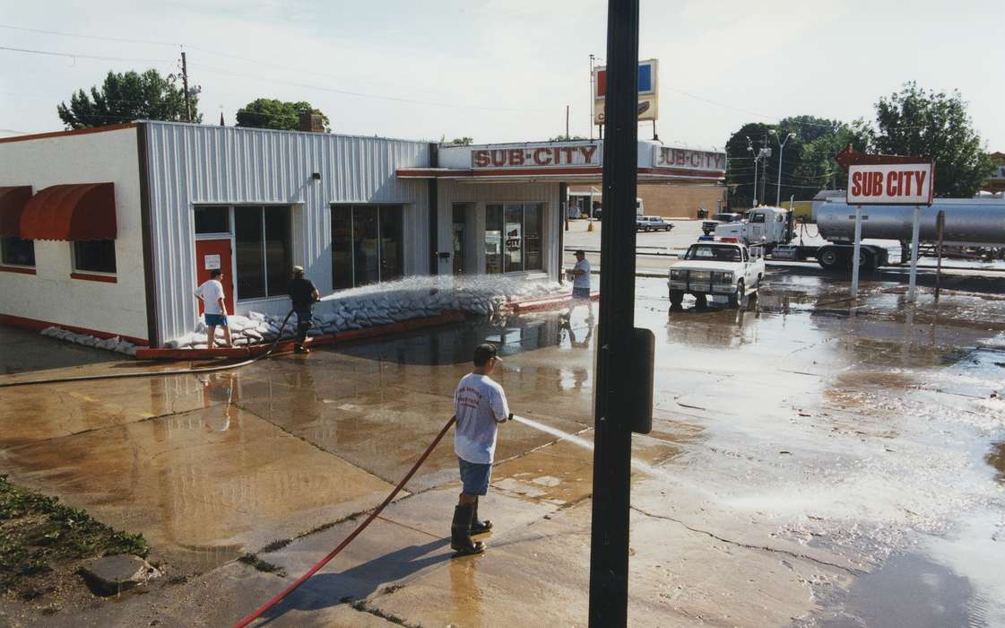 truck, hose, sub city, concrete, Civic Engagement, water, sandbag, Motorized Vehicles, sandwich, Iowa History, history of Iowa, Waverly Public Library, Waverly, IA, cleaning, Iowa, boots, Floods, Businesses and Factories