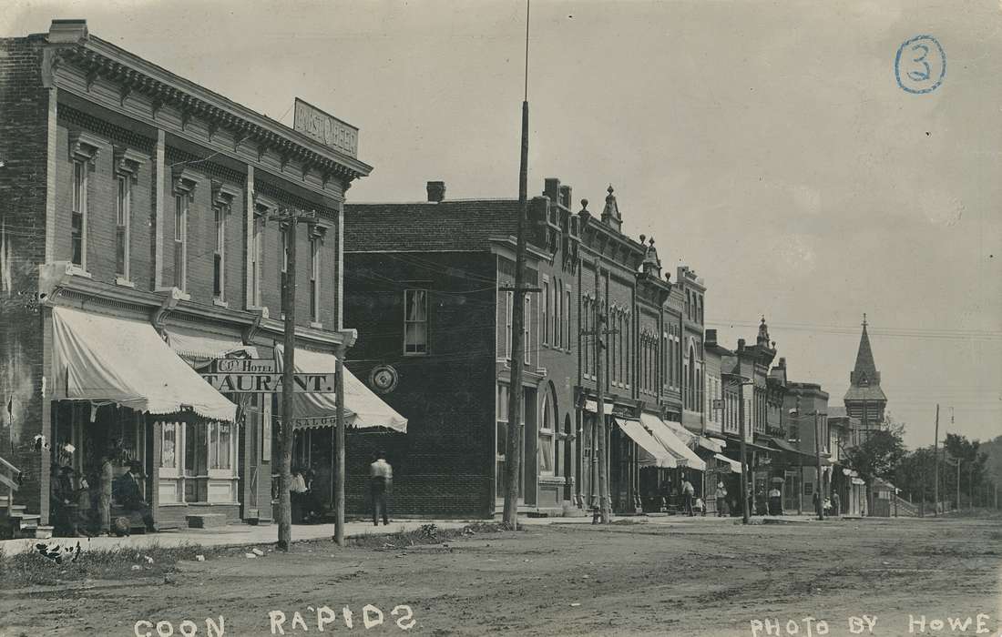 power line, sign, Businesses and Factories, Cities and Towns, People of Color, Coon Rapids Enterprise, Children, dirt road, Main Streets & Town Squares, Labor and Occupations, Religious Structures, awning, brick building