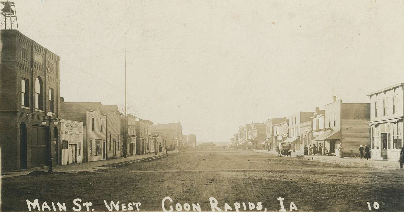 Motorized Vehicles, hat, correct date needed, Businesses and Factories, Cities and Towns, Coon Rapids Enterprise, Children, dirt road, Portraits - Group, Main Streets & Town Squares, car, awning, brick building