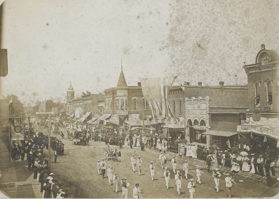 Cities and Towns, band uniform, carriage, american flag, Animals, clock, clock tower, parade, Aerial Shots, history of Iowa, Main Streets & Town Squares, umbrella, brick building, awning, Businesses and Factories, band, correct date needed, electrical pole, Waverly Public Library, Iowa History, Iowa, crowd, Entertainment, dirt street, horse