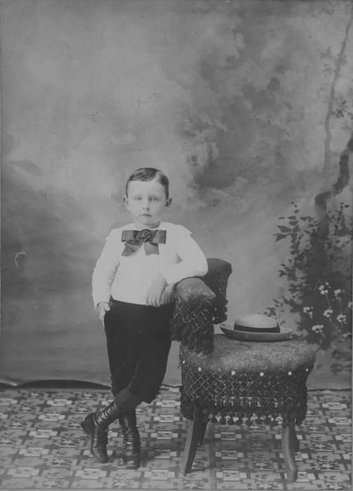 high buttoned shoes, painted backdrop, Becker, Alfred, floor cloth, Iowa, Children, Iowa History, chair, bow, hat, IA, knickers, Portraits - Individual, straw hat, bow tie, history of Iowa