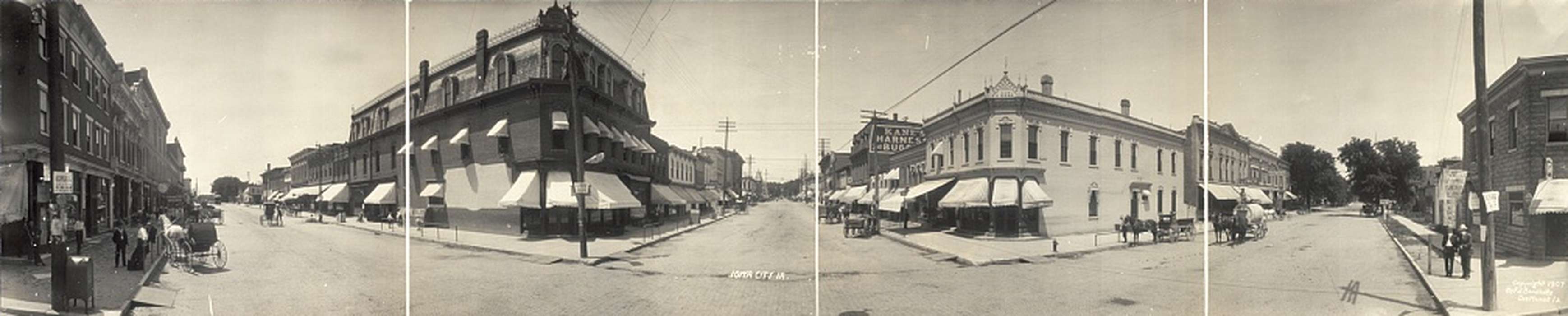 cobblestone street, horse and buggy, panorama, Main Streets & Town Squares, Businesses and Factories, power lines, kids, pedestrian, sidewalk, Iowa History, Children, storefront awning, Labor and Occupations, Portraits - Group, electrical pole, man, Library of Congress, Cities and Towns, horse and cart, woman, Families, Animals, horse, history of Iowa, Iowa, brick building, Leisure