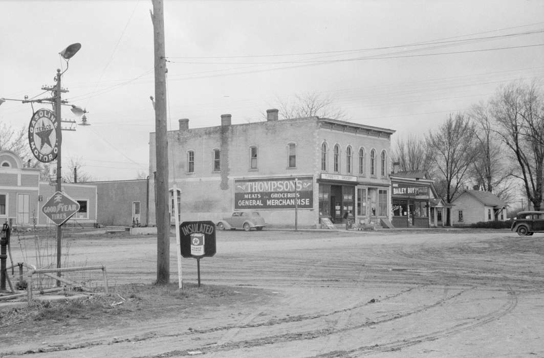 Businesses and Factories, general store, grocery store, dirt street, electrical pole, power lines, cars, Library of Congress, Cities and Towns, Motorized Vehicles, house, Iowa, Iowa History, brick building, tree, history of Iowa, pipeline, texaco