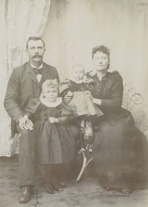 girl, family, woman, mustache, Iowa History, bow tie, cabinet photo, Kimballton, IA, Iowa, Portraits - Group, sack coat, wicker chair, siblings, history of Iowa, patterned carpet, Families, painted backdrop, Olsson, Ann and Jons, Children, man