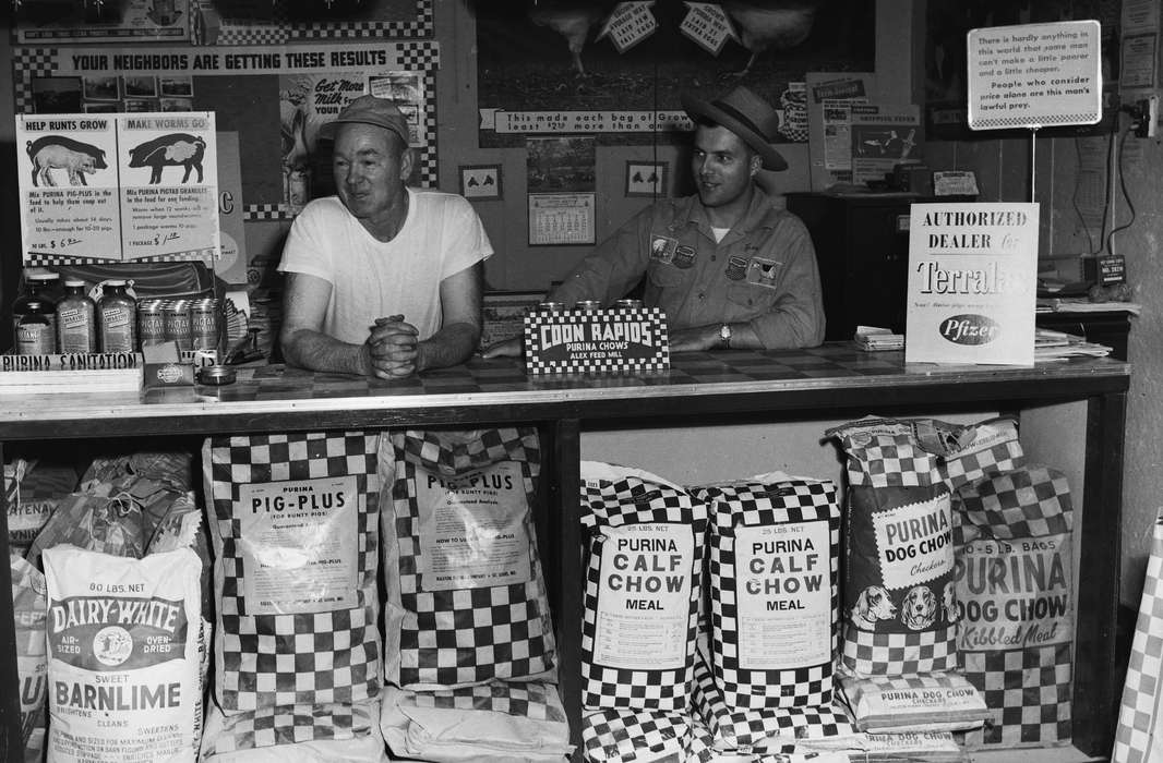 Businesses and Factories, Food and Meals, history, Photos, Labor and Occupations, dog food, Animals, Iowa, animal feed, IA, baseball cap, two men, United States, ia, purina, Coon Rapids Enterprise, panama hat, historic, Coon Rapids