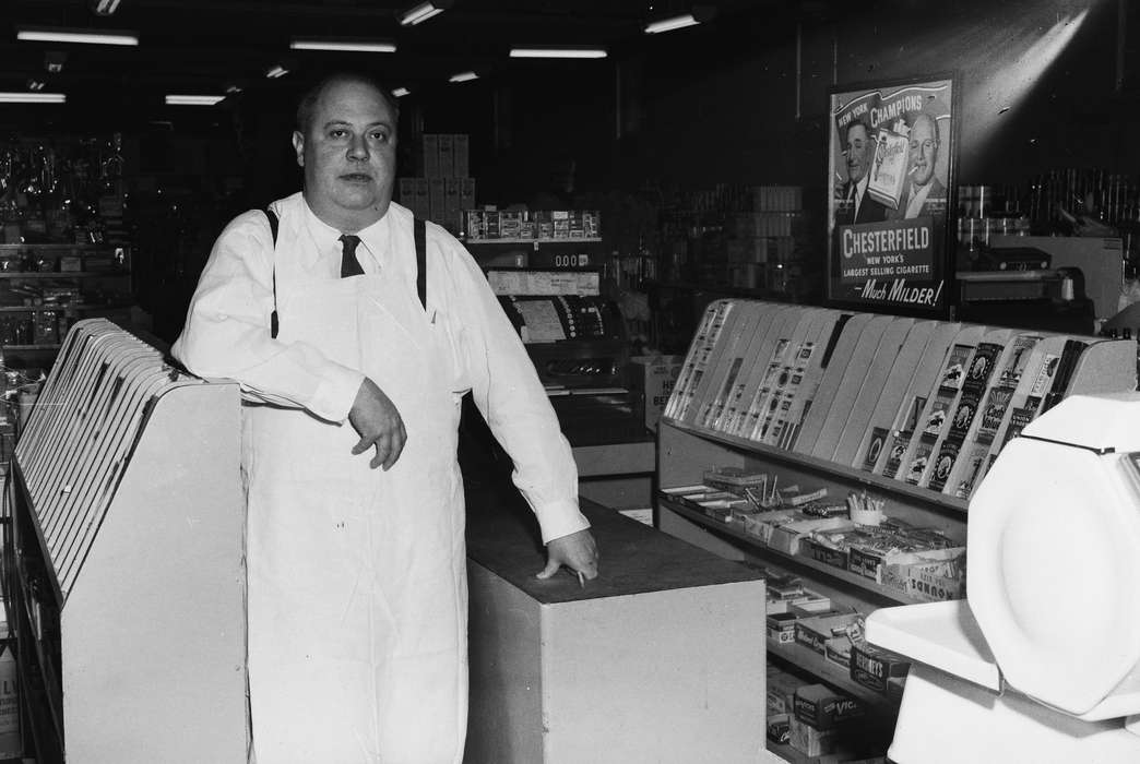 Businesses and Factories, employee, history, Photos, Labor and Occupations, cash register, apron, Iowa, IA, advertisement, Portraits - Individual, United States, ia, grocery store, Coon Rapids Enterprise, cigarettes, necktie, historic, candy, Coon Rapids